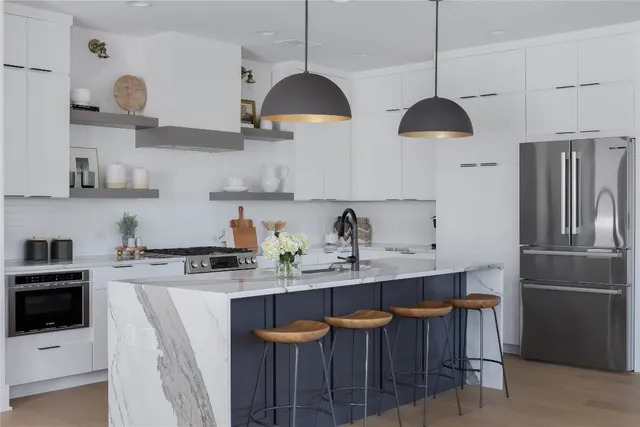 a kitchen with stainless steel appliances granite countertop a sink a stove a refrigerator and island with wooden floor