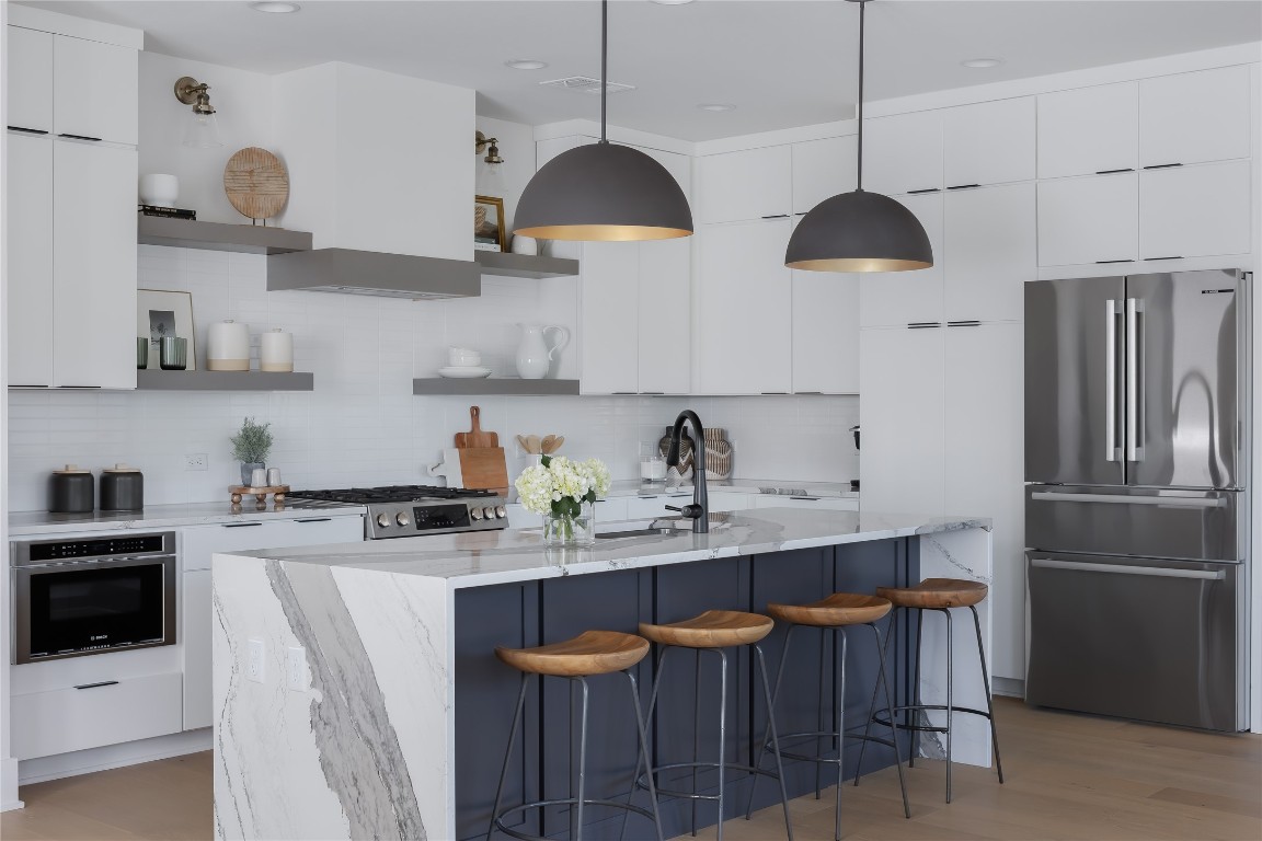 7809 Old Bee Caves Road, Unit 13 Austin, TX 78735 - Photo 9 of 30 a kitchen with stainless steel appliances granite countertop a sink a stove a refrigerator and island with wooden floor