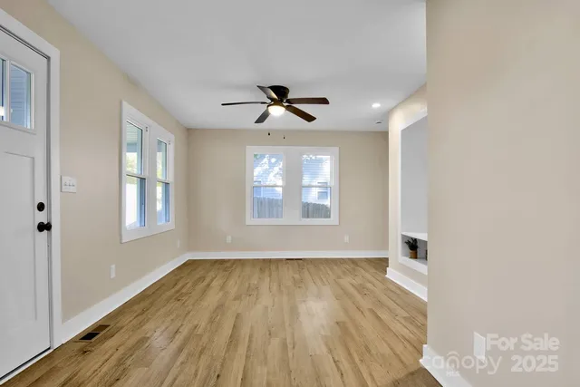 a view of an empty room with a window and wooden floor