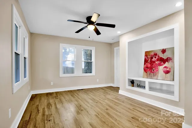 a view of an empty room with window and wooden floor