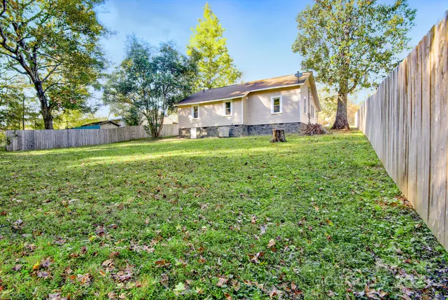 a backyard of a house with table and chairs plants and large tree