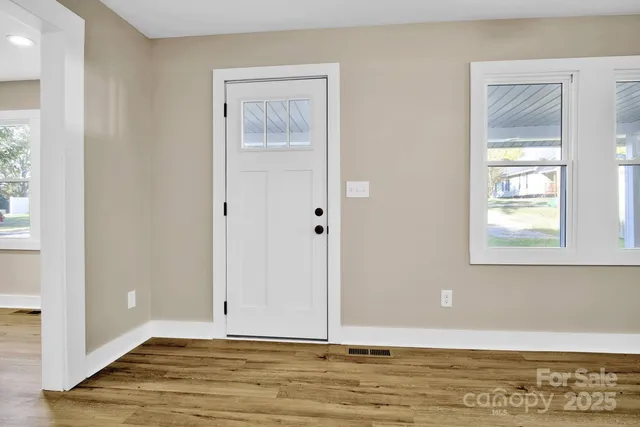 a view of an empty room with window and wooden floor