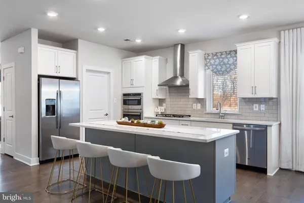 a kitchen with stainless steel appliances granite countertop a sink a stove a refrigerator cabinets and chairs