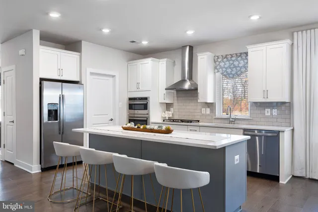 a kitchen with stainless steel appliances granite countertop a sink a stove a refrigerator cabinets and chairs