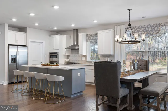a kitchen with kitchen island granite countertop a dining table chairs stainless steel appliances and cabinets
