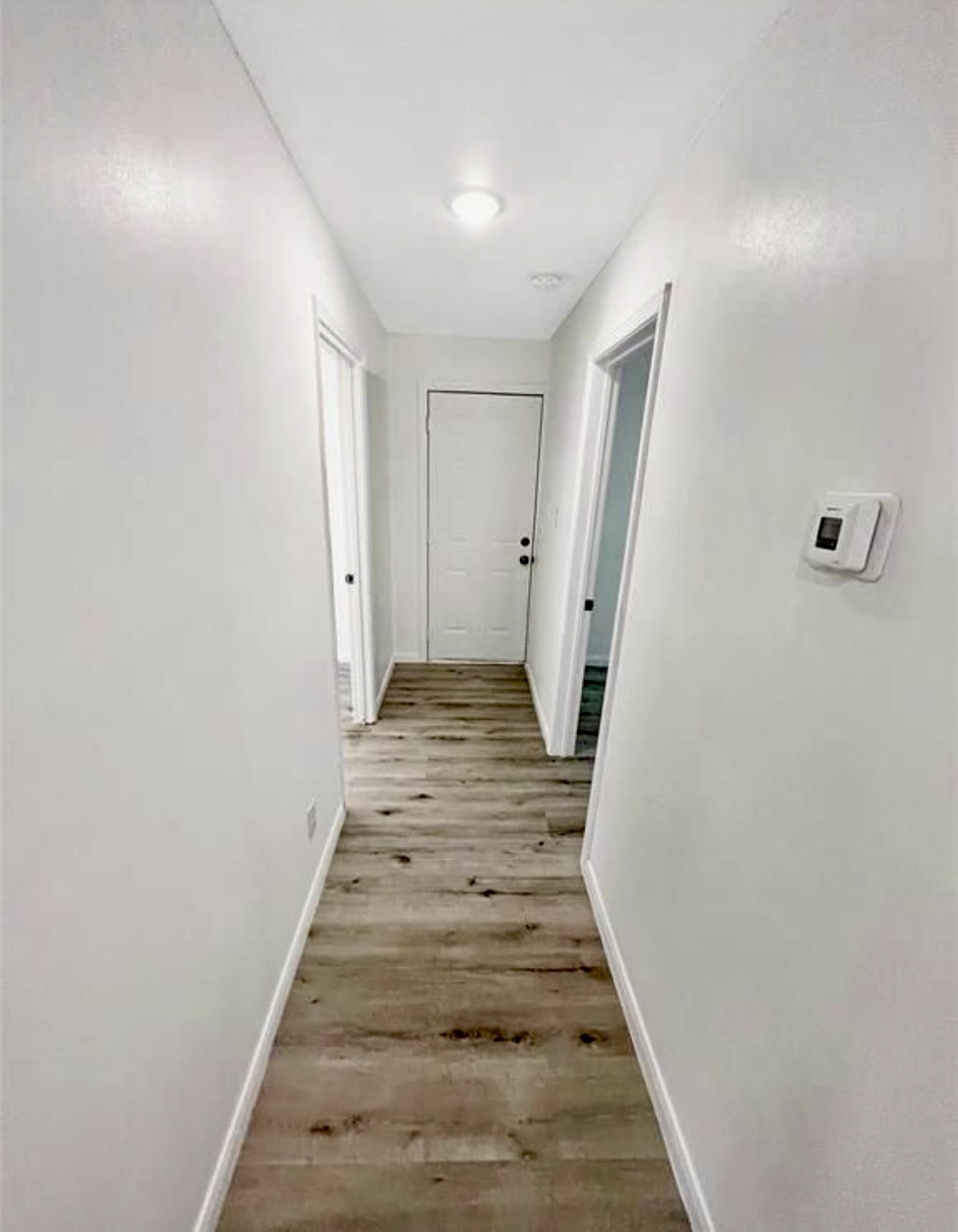 408 Commanche Road Conroe, TX 77316 - Photo 14 of 25 Bright hallway with sleek wood flooring and crisp white walls, leading to multiple rooms for easy access.