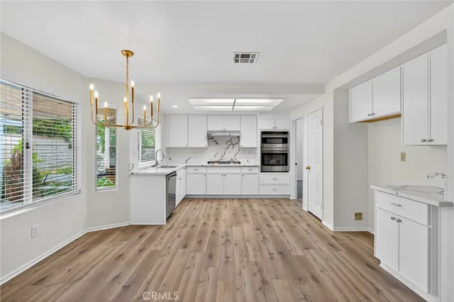 a kitchen with white cabinets and wooden floor