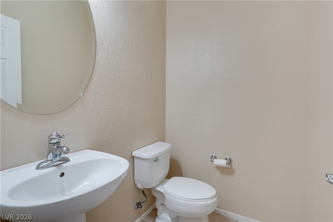2717 Rimbaud Street Henderson, NV 89044 - Photo 13 of 34 A pristine powder room offers a simple pedestal sink and round mirror.