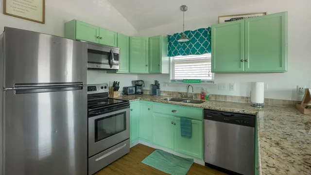a kitchen with granite countertop a sink stainless steel appliances and cabinets