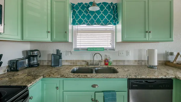 a kitchen with granite countertop a sink a stove and cabinets