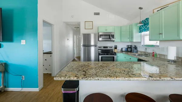 a kitchen with kitchen island granite countertop a sink a stove counter space and refrigerator