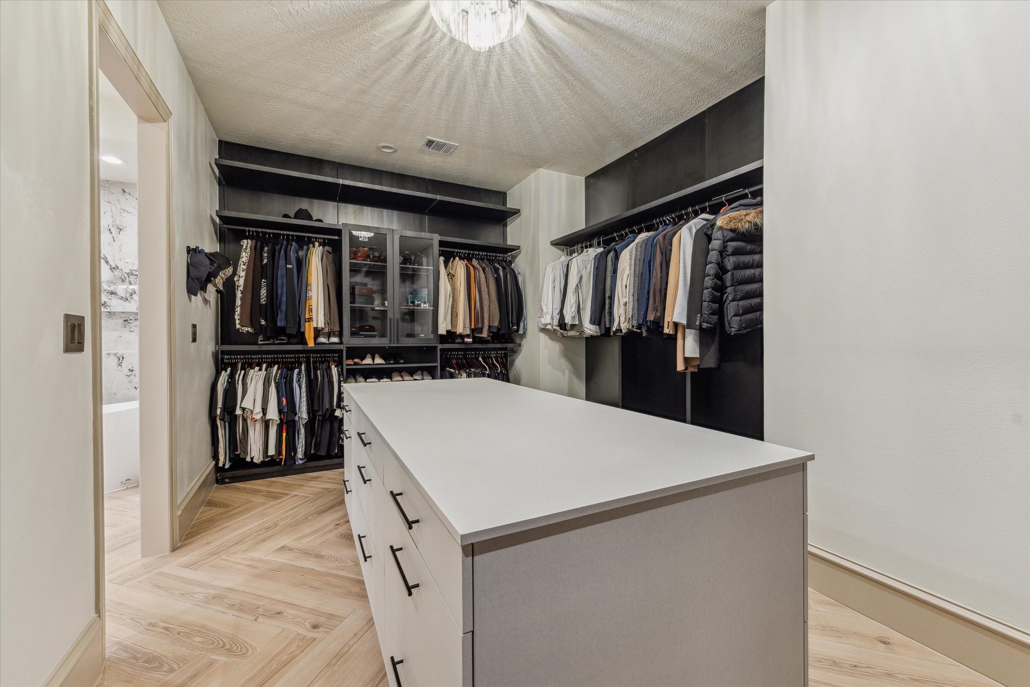 918 Huntington Cove Houston, TX 77063 - Photo 44 of 50 Expansive primary. dressing room anchored by a large center island complemented by multiple levels of storage and hanging racks.