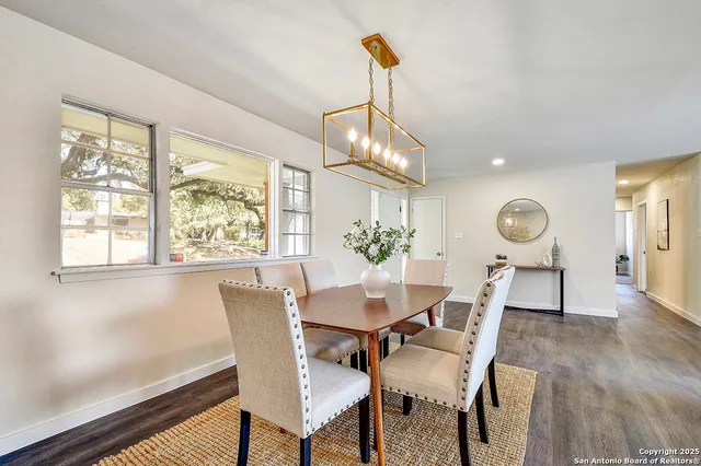 a dining room with chandelier and wooden floor