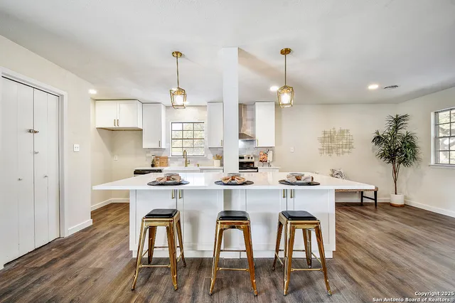 a kitchen with sink a stove and white cabinets with wooden floor