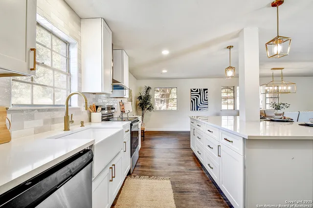 a large kitchen with granite countertop a large counter top space a sink stainless steel appliances and windows