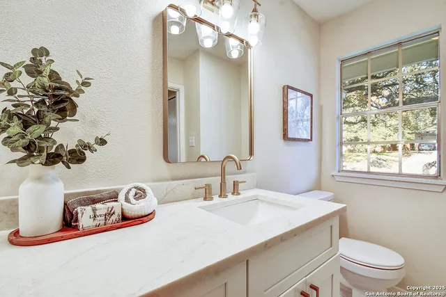 a bathroom with a granite countertop sink a large mirror and a toilet