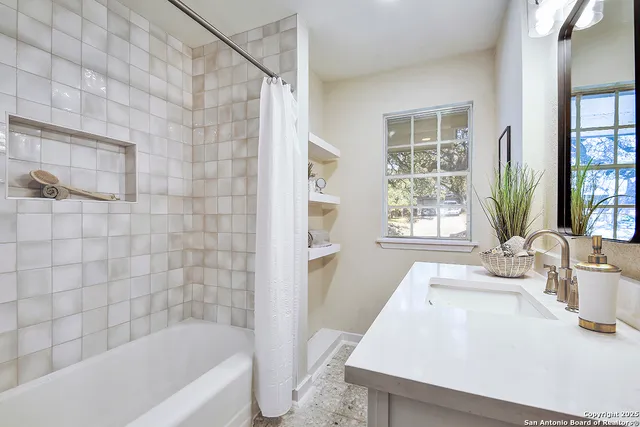 a bathroom with a sink a bathtub and next to a window