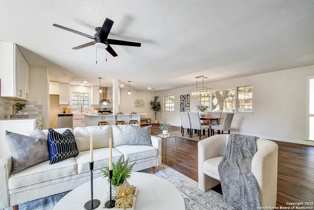 a living room with furniture kitchen view and a large window