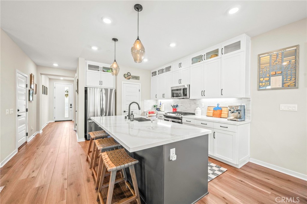 1281 Roots Way Rancho Mission Viejo, CA 92694 - Photo 15 of 75 a kitchen with stainless steel appliances a stove a sink a refrigerator and white cabinets with wooden floor