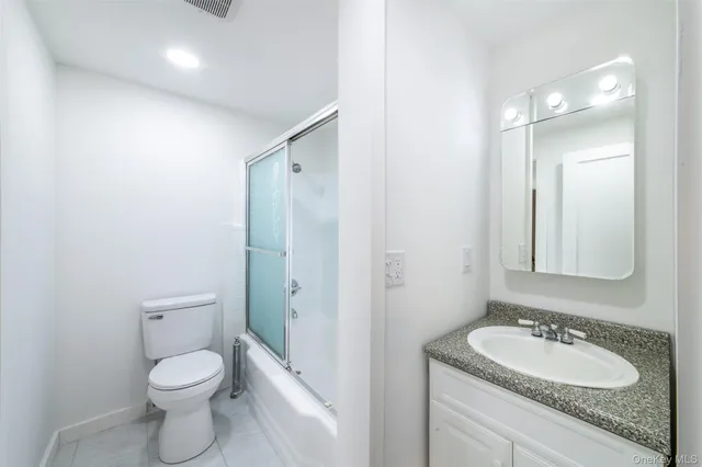 a bathroom with a granite countertop toilet a sink and a mirror