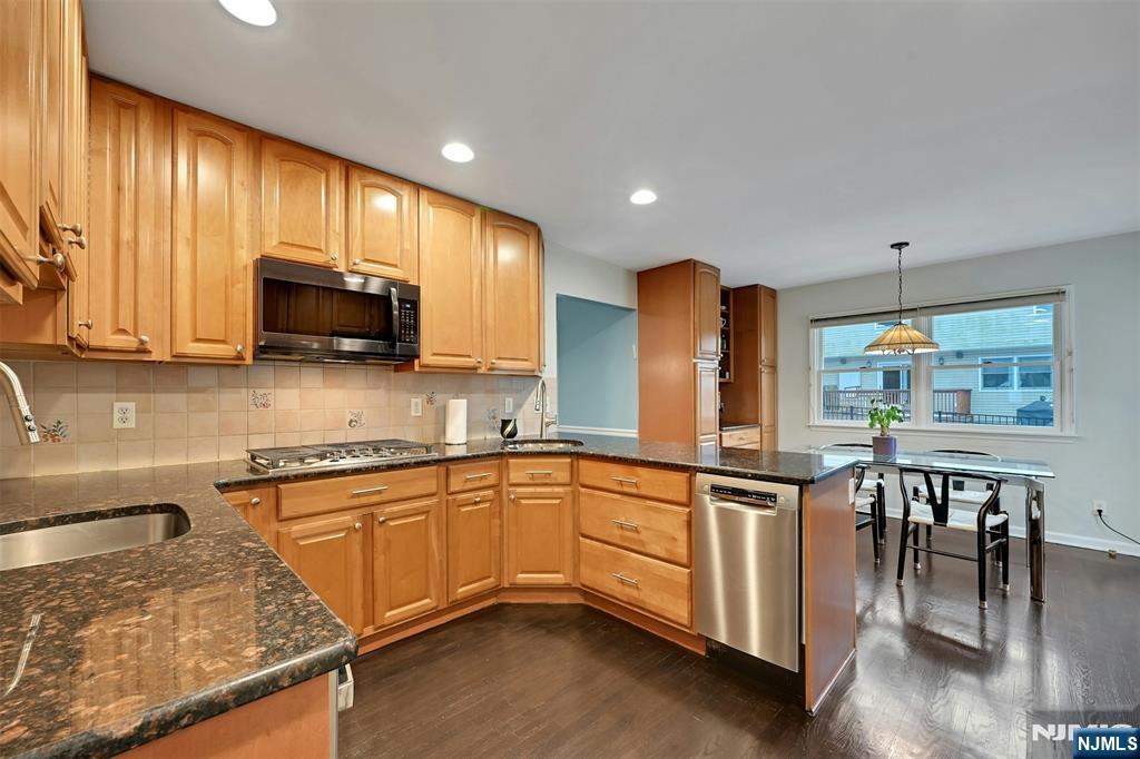 288 Schley Place Teaneck, NJ 07666 - Photo 4 of 29 a kitchen with stainless steel appliances granite countertop wooden cabinets a sink a stove a dining table and chairs