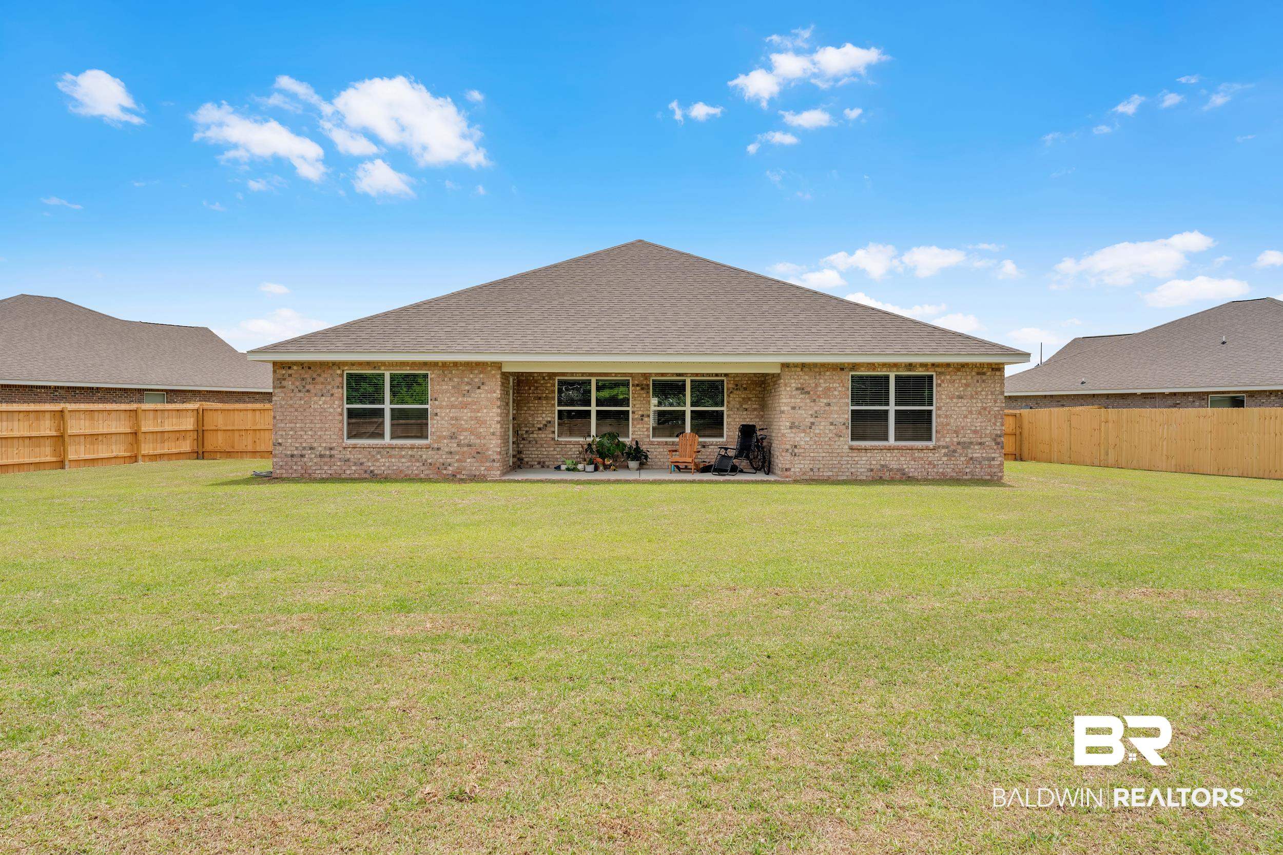 24460 Ringneck Loop Elberta, AL 36530 - Photo 8 of 46 Back of house featuring brick siding, a fenced backyard, and a lawn