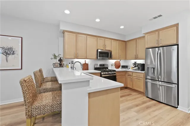 a kitchen with stainless steel appliances granite countertop a refrigerator a stove a sink a dining table and chairs