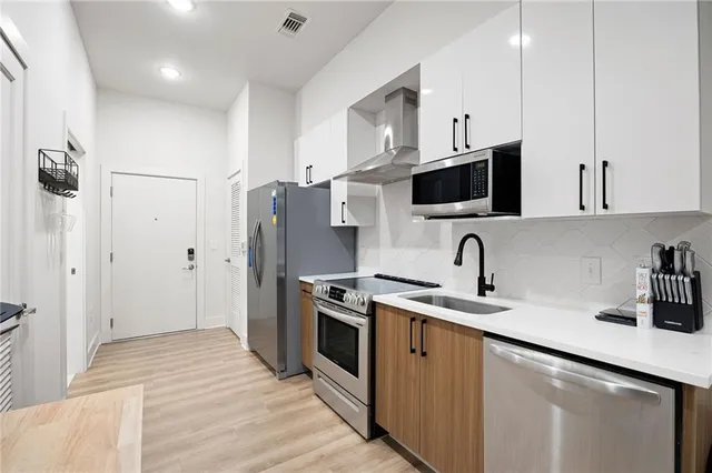 a kitchen with stainless steel appliances granite countertop a sink a stove a refrigerator and cabinets