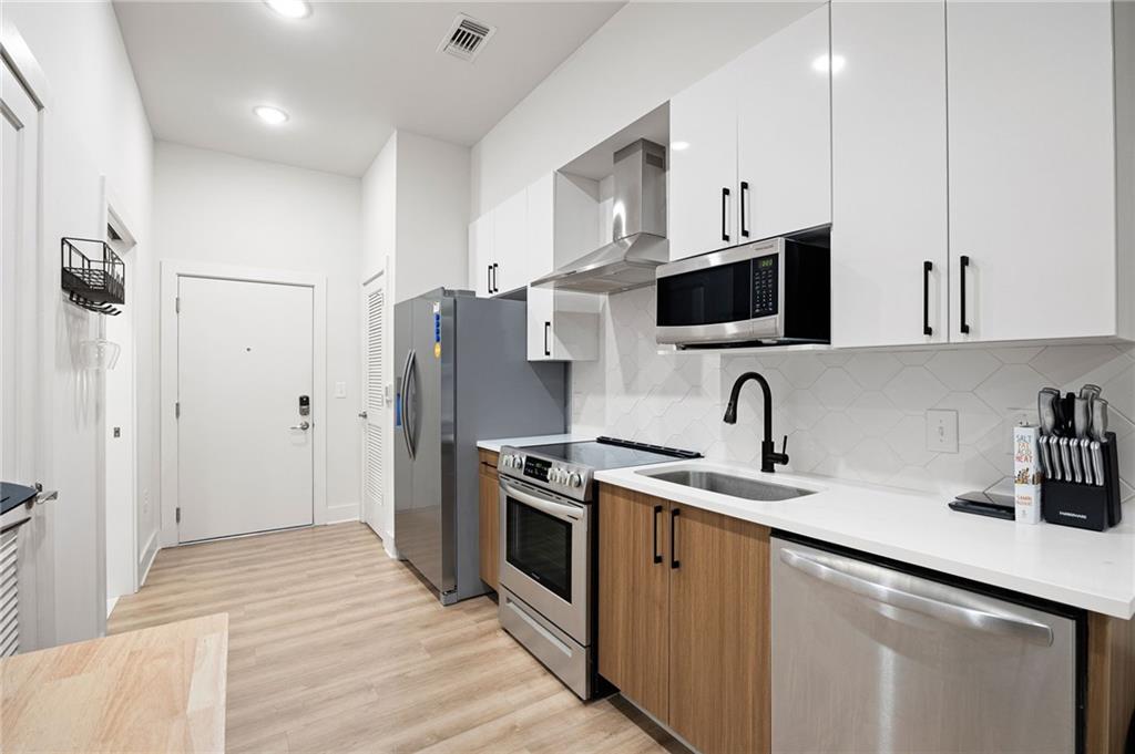 112 Rogers Street Northeast, Unit 202 Atlanta, GA 30317 - Photo 3 of 36 a kitchen with stainless steel appliances granite countertop a sink a stove a refrigerator and cabinets