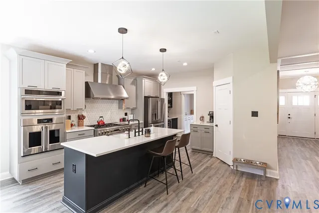 a living room with stainless steel appliances kitchen island granite countertop a couch a dining table and chairs with wooden floor