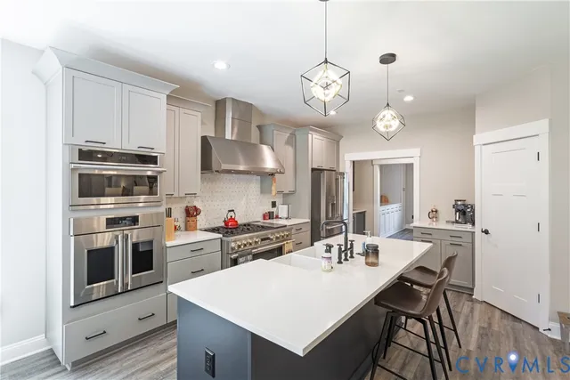 a kitchen with a sink appliances and wooden floor