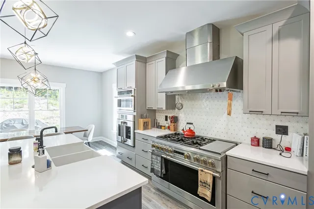 a kitchen with stainless steel appliances a dining table chairs stove refrigerator and cabinets