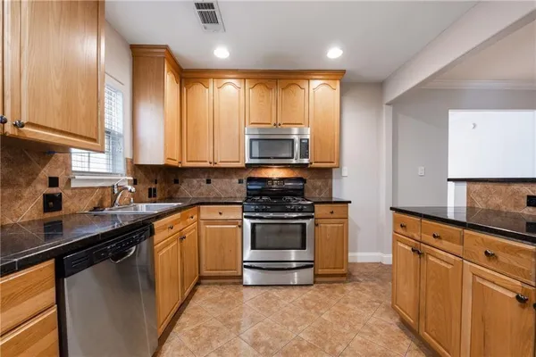 a kitchen with stainless steel appliances granite countertop a stove a sink and a microwave