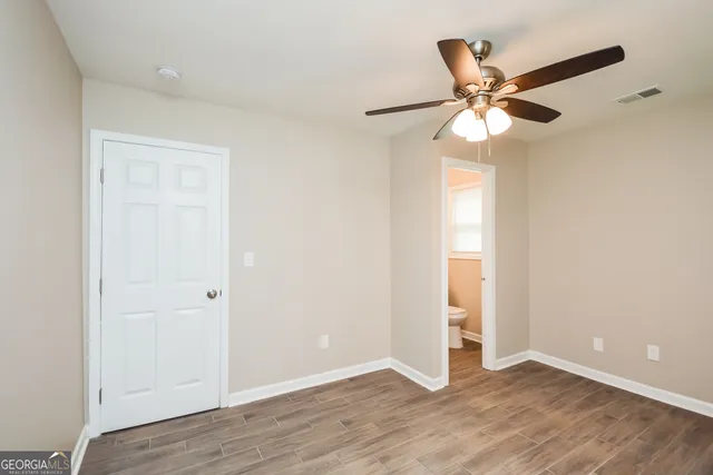 an empty room with wooden floor closet and fan