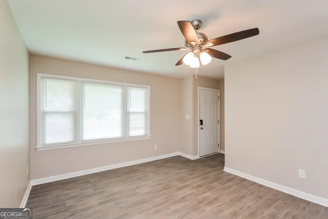 a view of an empty room with wooden floor and a window