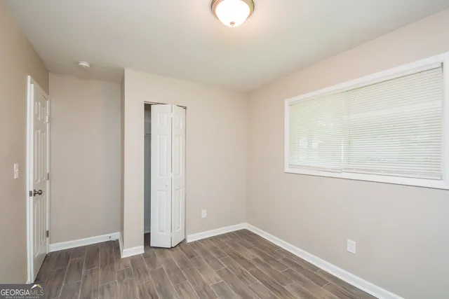 an empty room with wooden floor and window