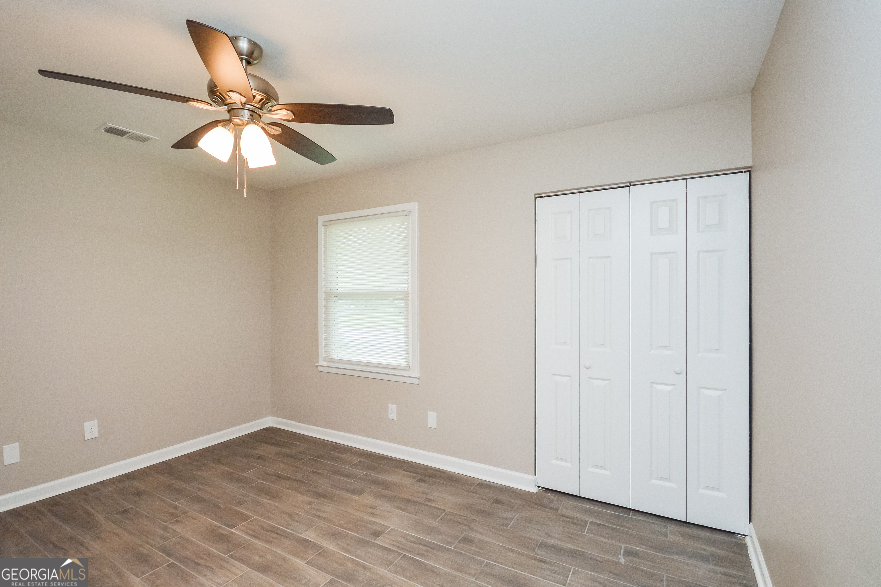 1534 Flicker Road Hampton, GA 30228 - Photo 10 of 16 an empty room with wooden floor fan and windows