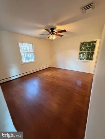 an empty room with windows and fan