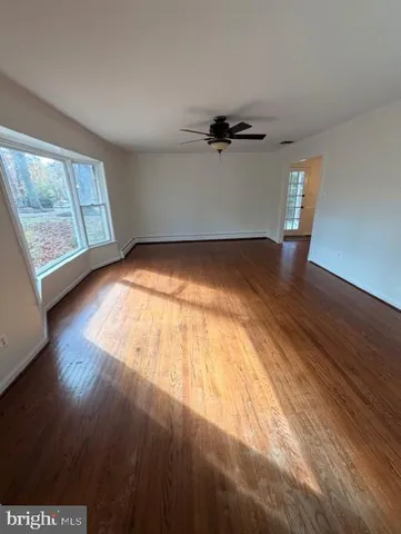 an empty room with wooden floor cabinet and windows