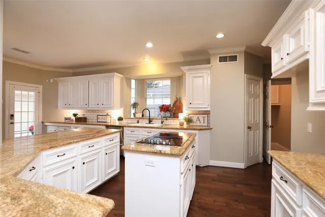 a kitchen with stainless steel appliances granite countertop a refrigerator a sink dishwasher and white cabinets with wooden floor