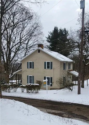 a view of a white house with a yard covered in snow