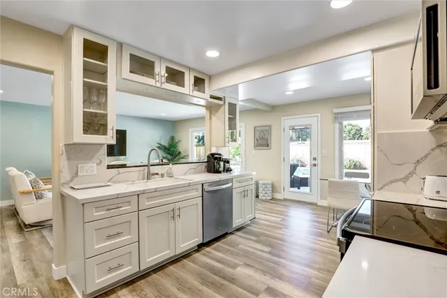 a kitchen with kitchen island granite countertop a dining table chairs sink and cabinets