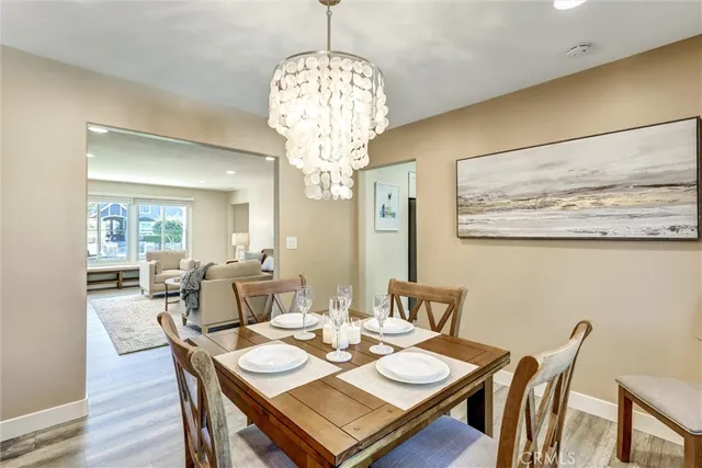 a kitchen with stainless steel appliances granite countertop a stove top oven a sink dishwasher a refrigerator and a dining table with wooden floor