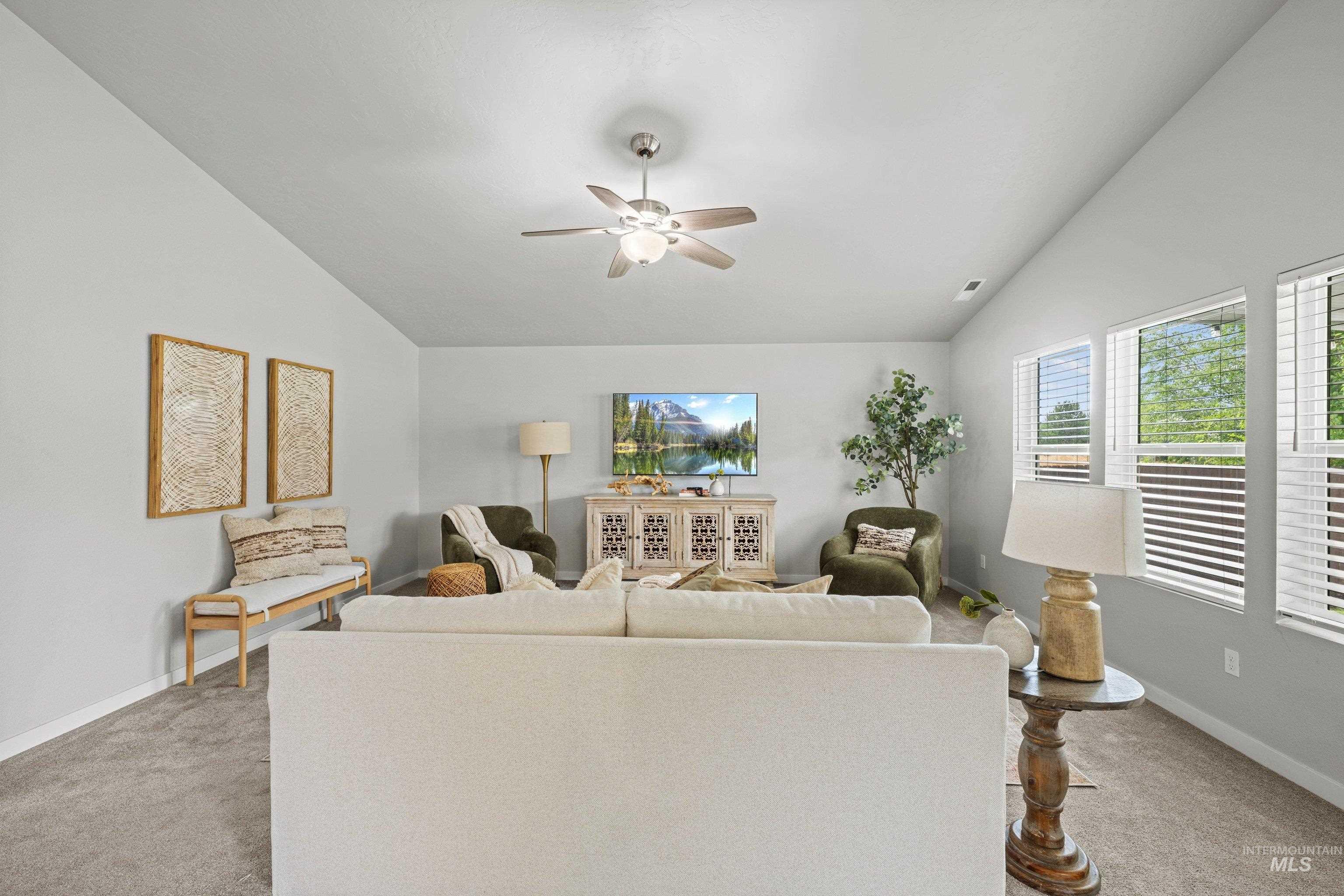 12744 West Fig Street Boise, ID 83713 - Photo 7 of 34 Spacious living area featuring a vaulted ceiling with a ceiling fan, carpet flooring, multiple windows with blinds, and a neutral wall color