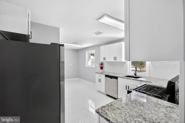 a kitchen with stainless steel appliances a refrigerator a sink a stove and white cabinets