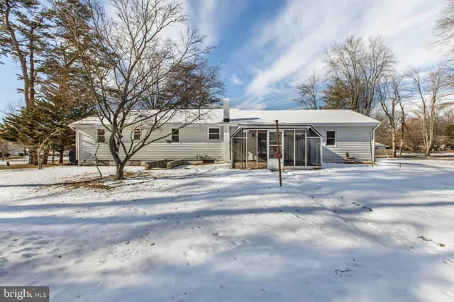 a view of a white house with a large tree covered with snow