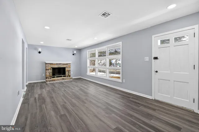 an empty room with wooden floor a fireplace and windows