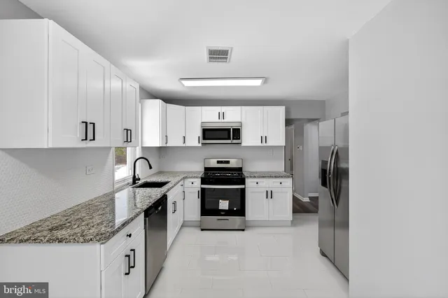a kitchen with stainless steel appliances granite countertop a stove sink and refrigerator