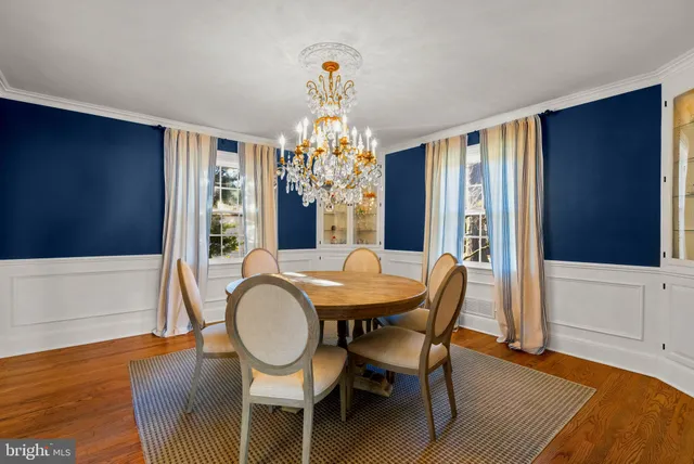 a dining room with chandelier and wooden floor