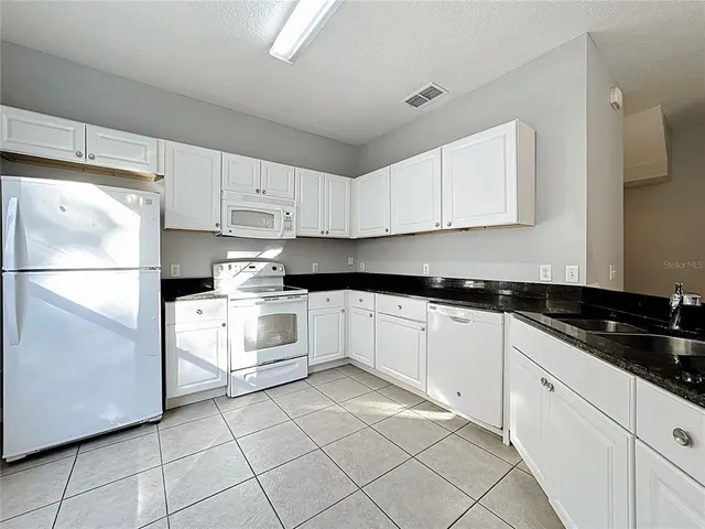 a kitchen with granite countertop white cabinets and white appliances